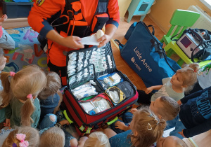 Dzieci oglądają środki pierwszej pomocy w walizce ratowniczej.